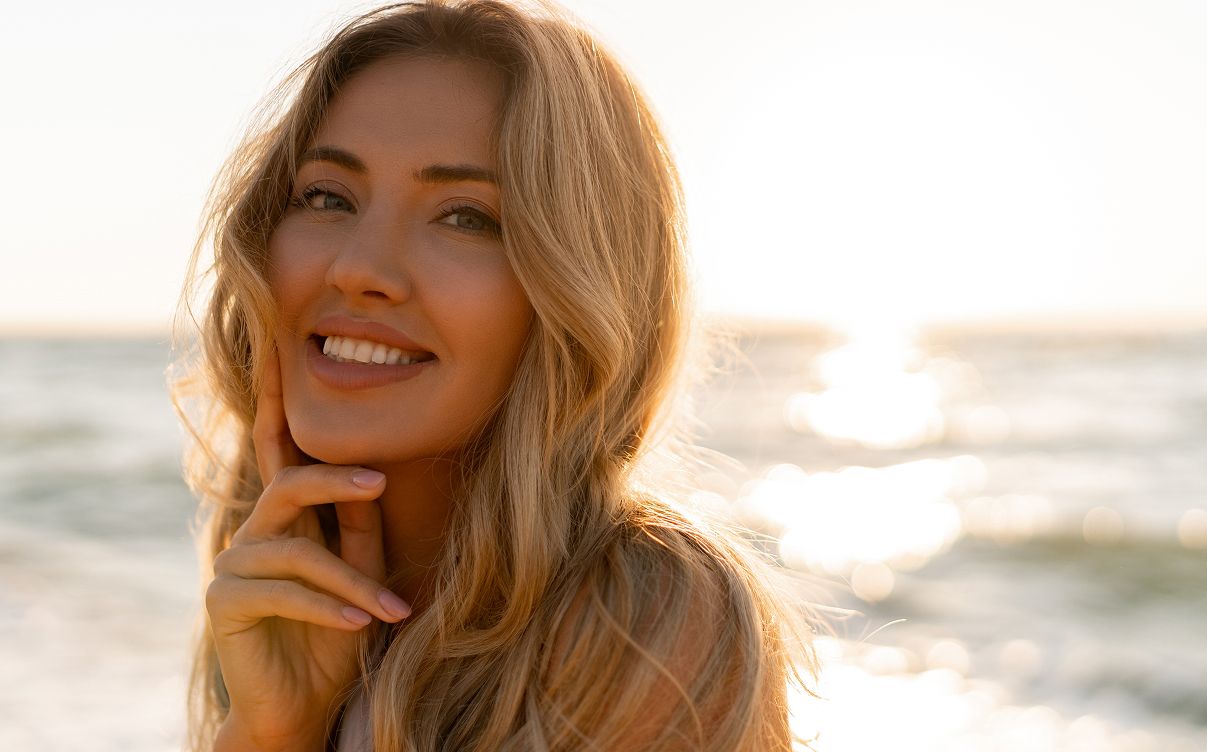 Smiling woman at the beach during sunset.