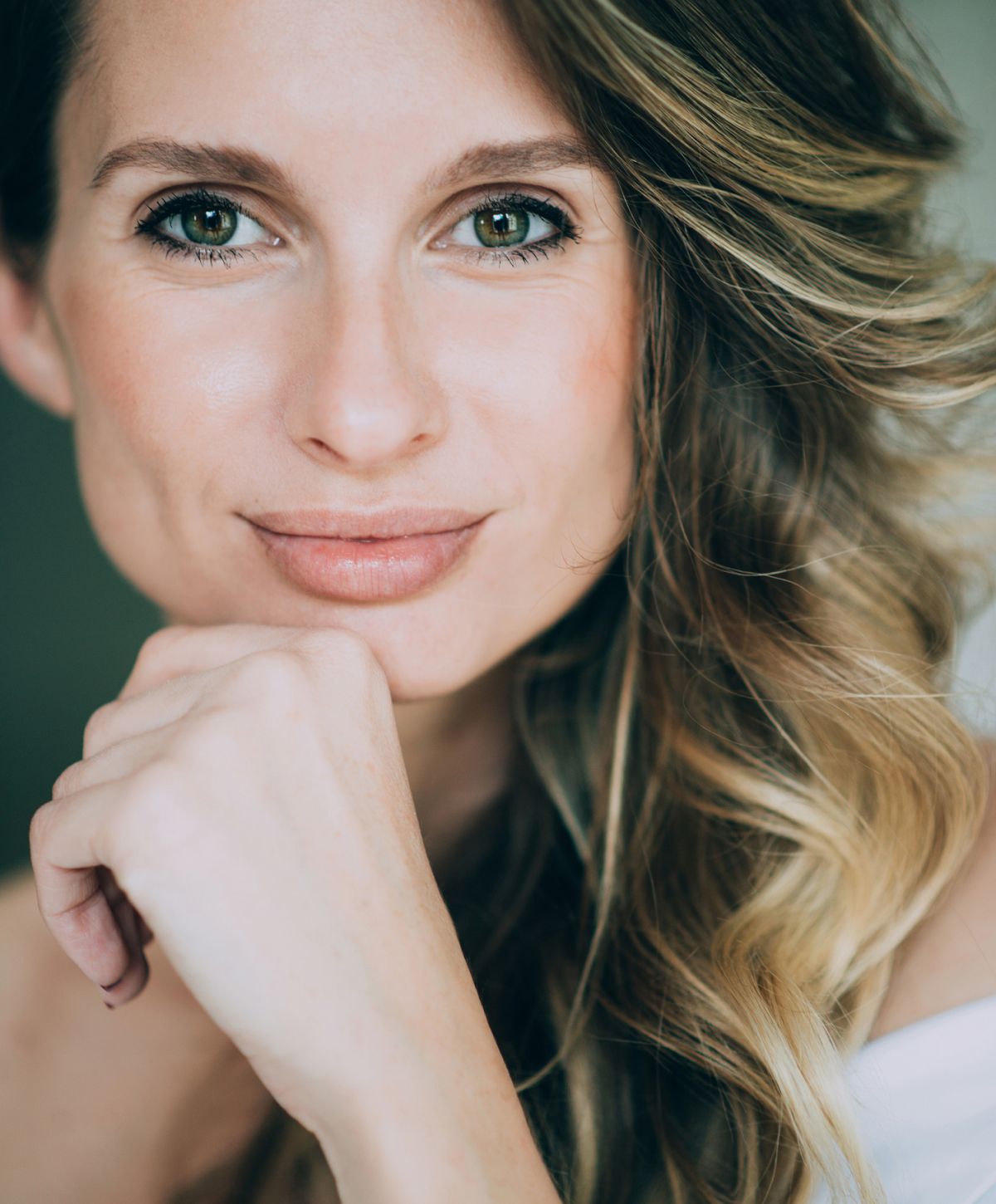 Woman resting chin on hand, smiling confidently.