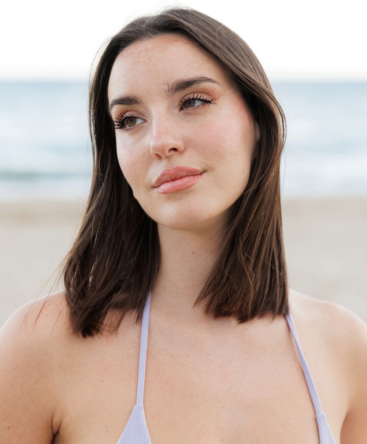 Woman gazing thoughtfully at the beach.