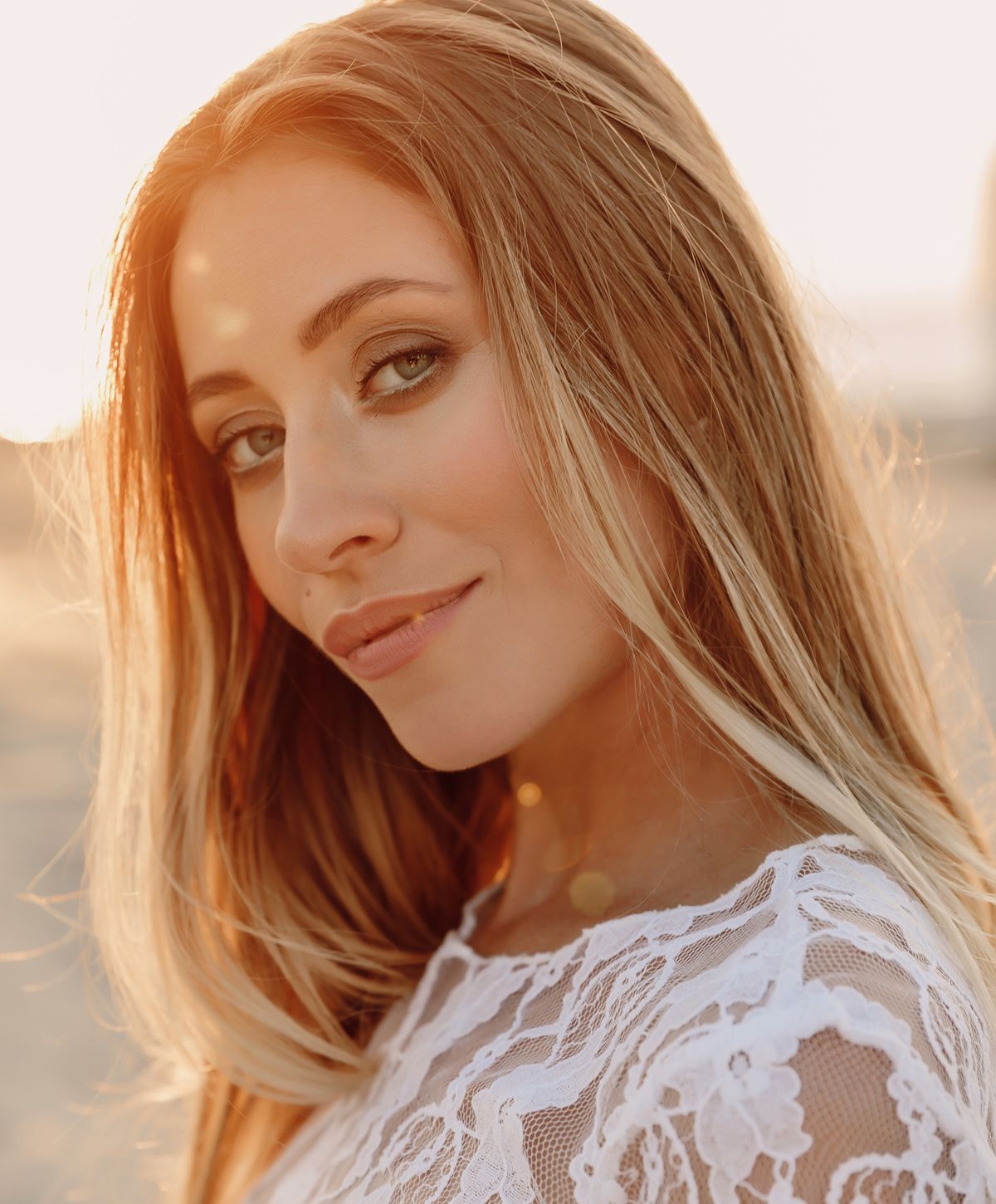 Woman in white lace dress, sunny background.