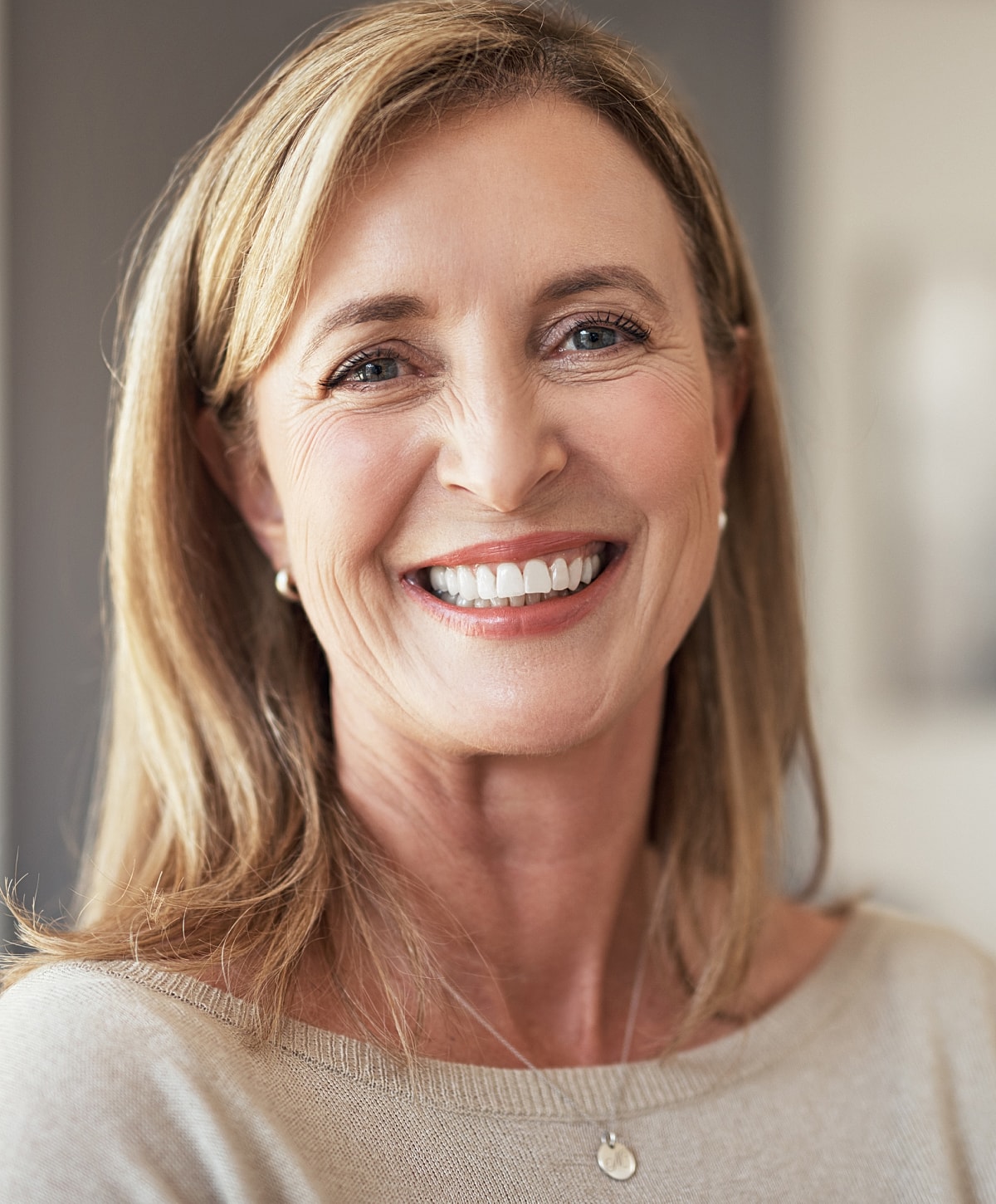 Smiling woman in casual sweater, indoors setting.