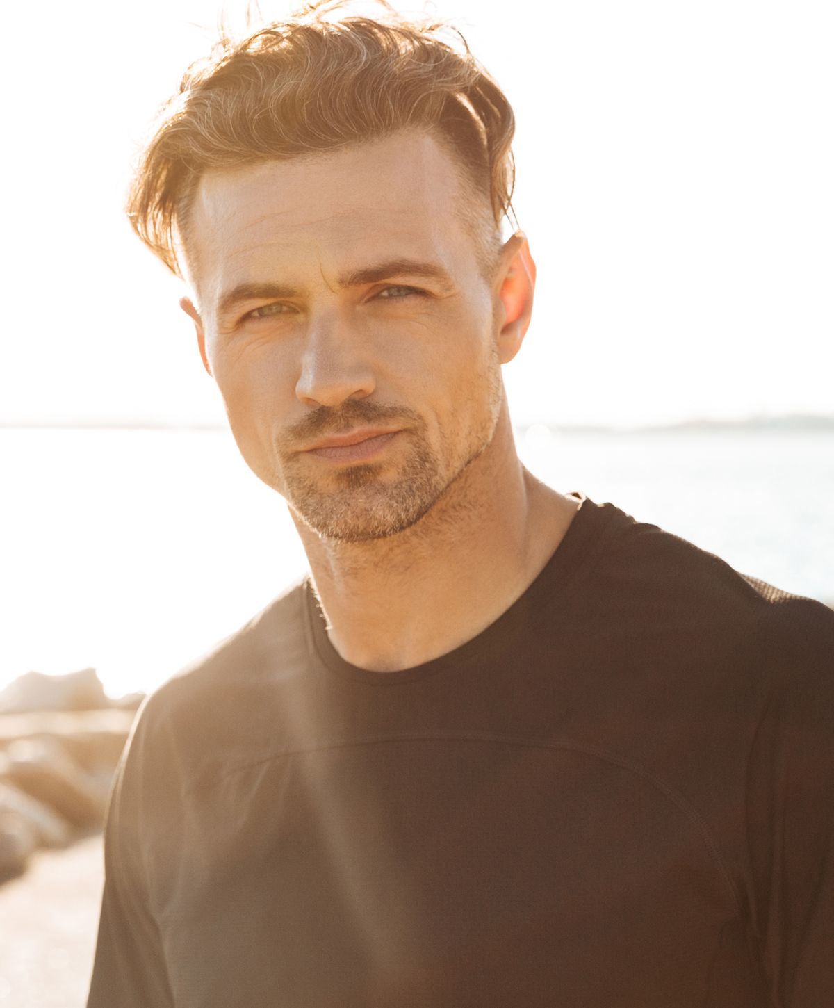 Man smiling with sunlight in background.