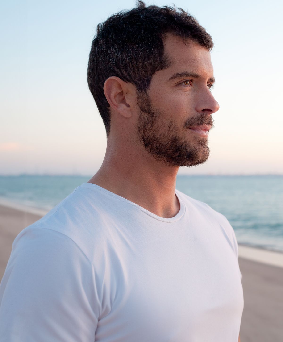 Man standing by the beach at sunset.