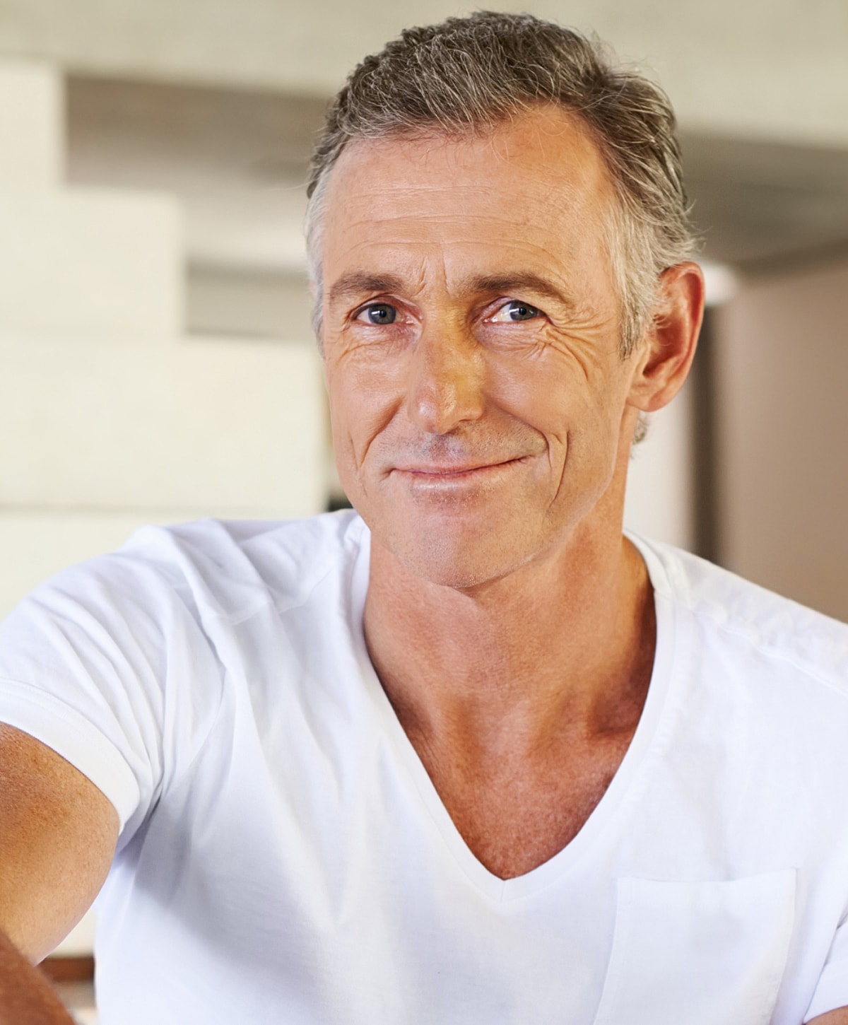 Smiling man in casual white shirt indoors.