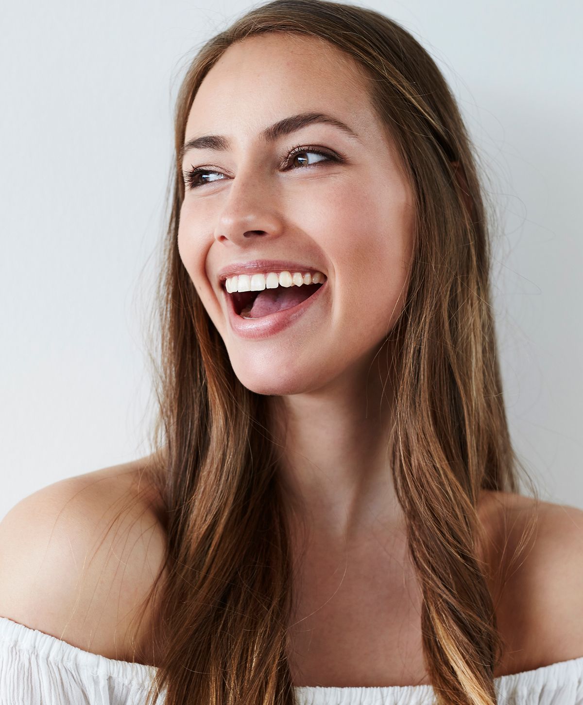 Smiling woman with long hair against white background.