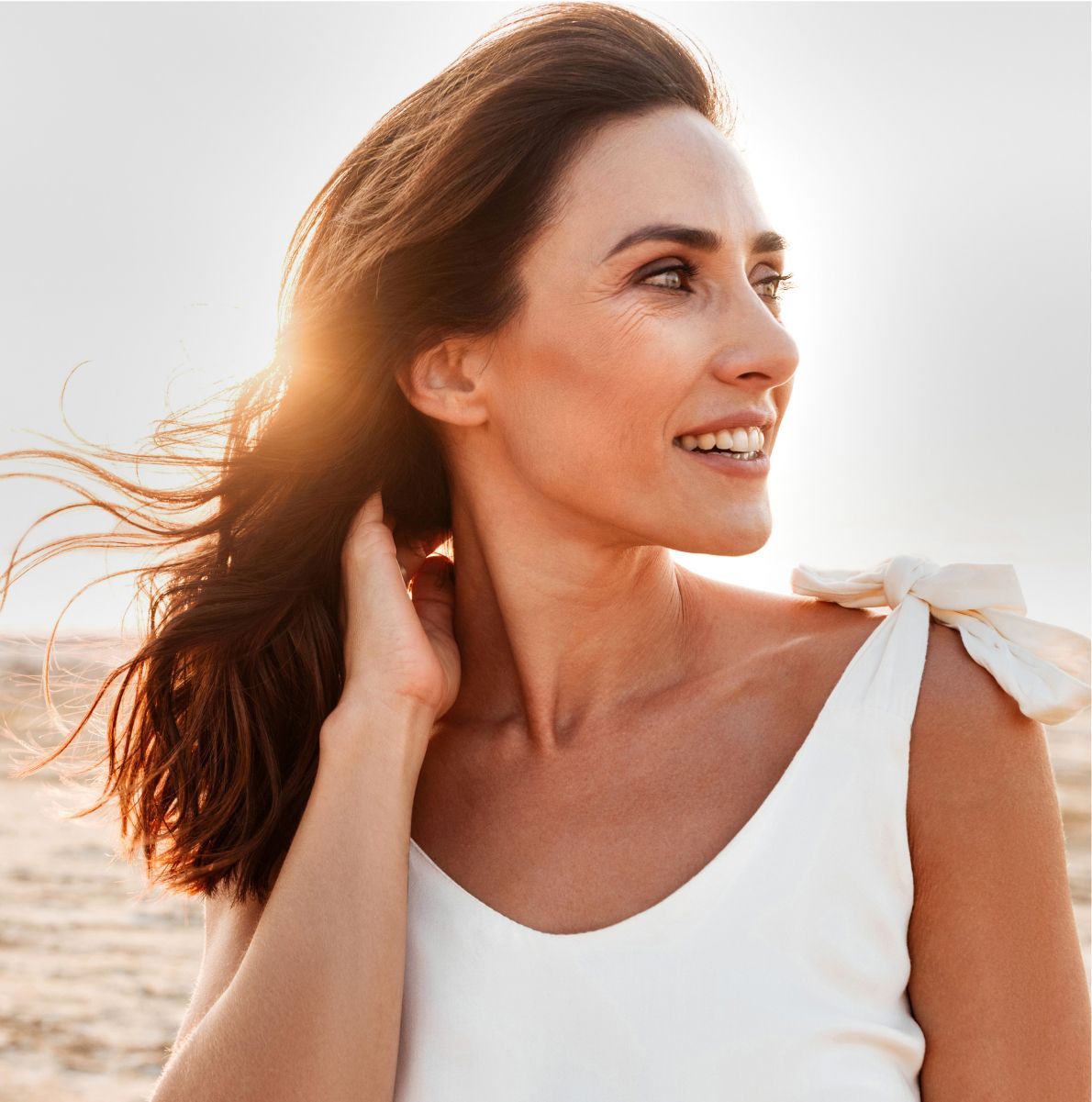 Smiling woman outdoors with flowing hair.