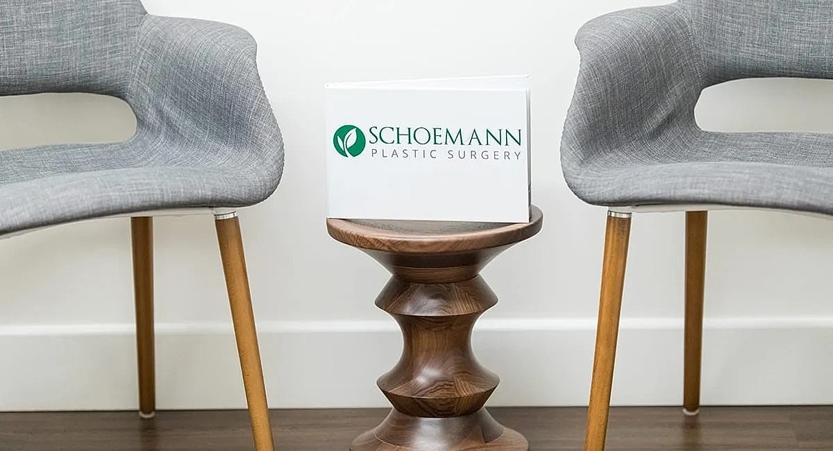 Waiting area with chairs and plastic surgery sign.