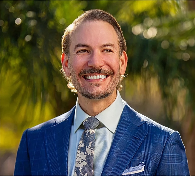 Smiling man in a blue suit outdoors.