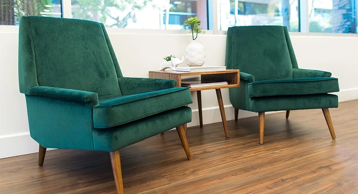 Green velvet chairs with wooden legs and table.