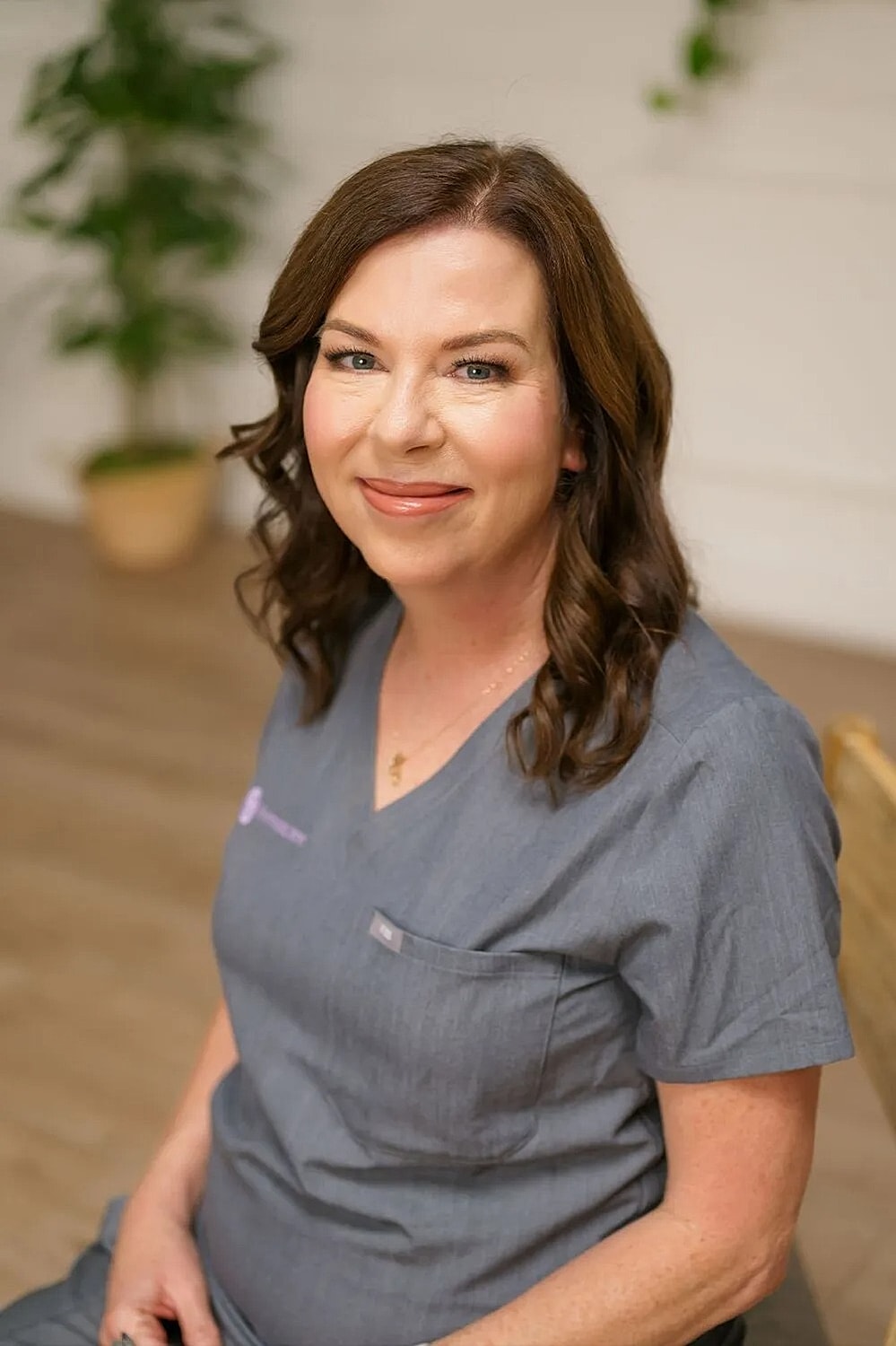 Smiling woman in medical scrubs, indoor setting.