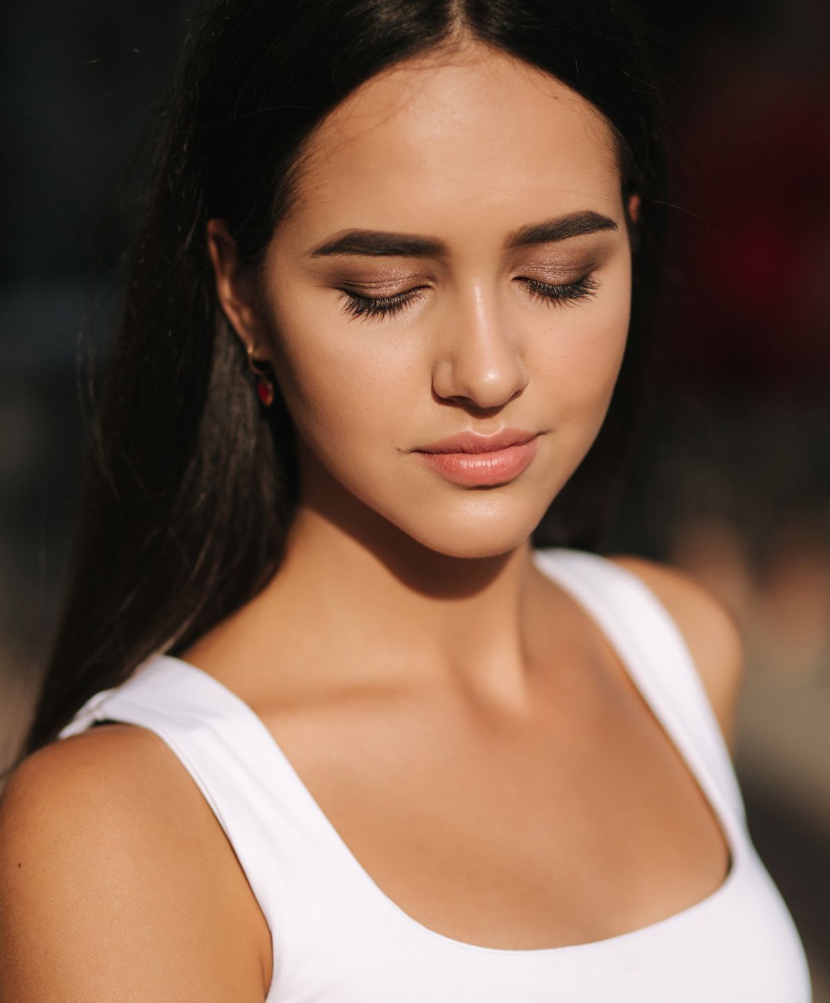 Woman with closed eyes, natural makeup in sunlight.