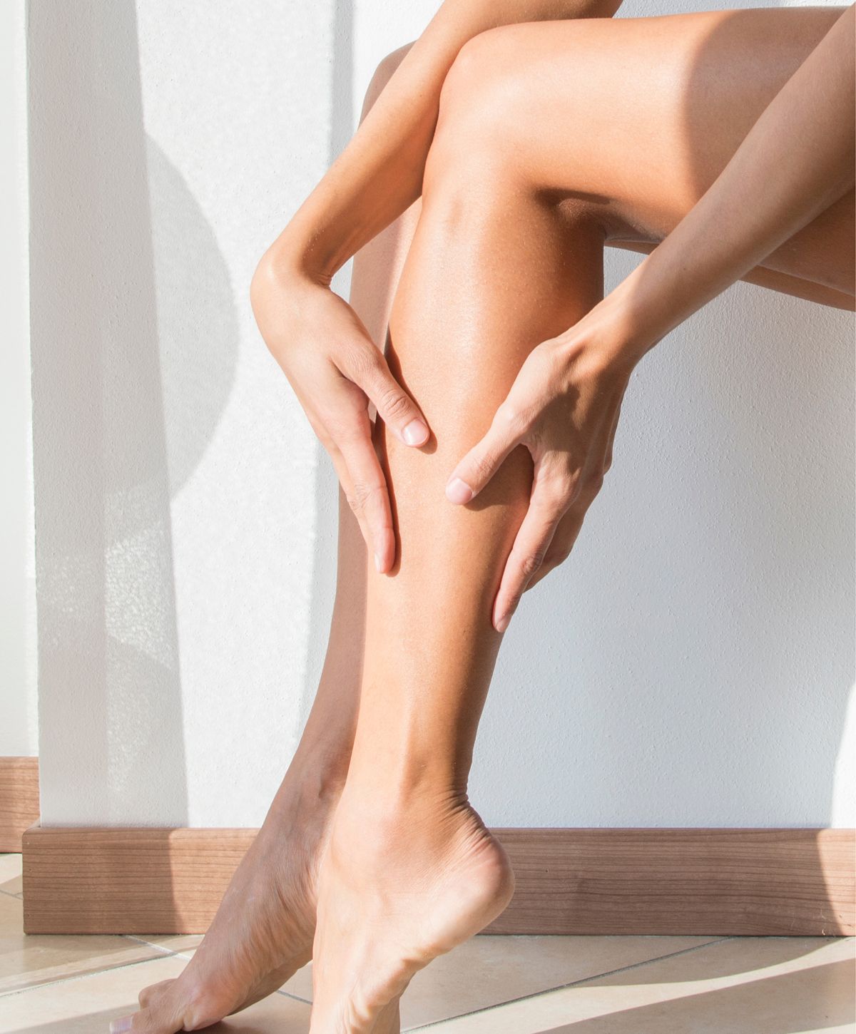 Person resting hand on leg in sunlight.