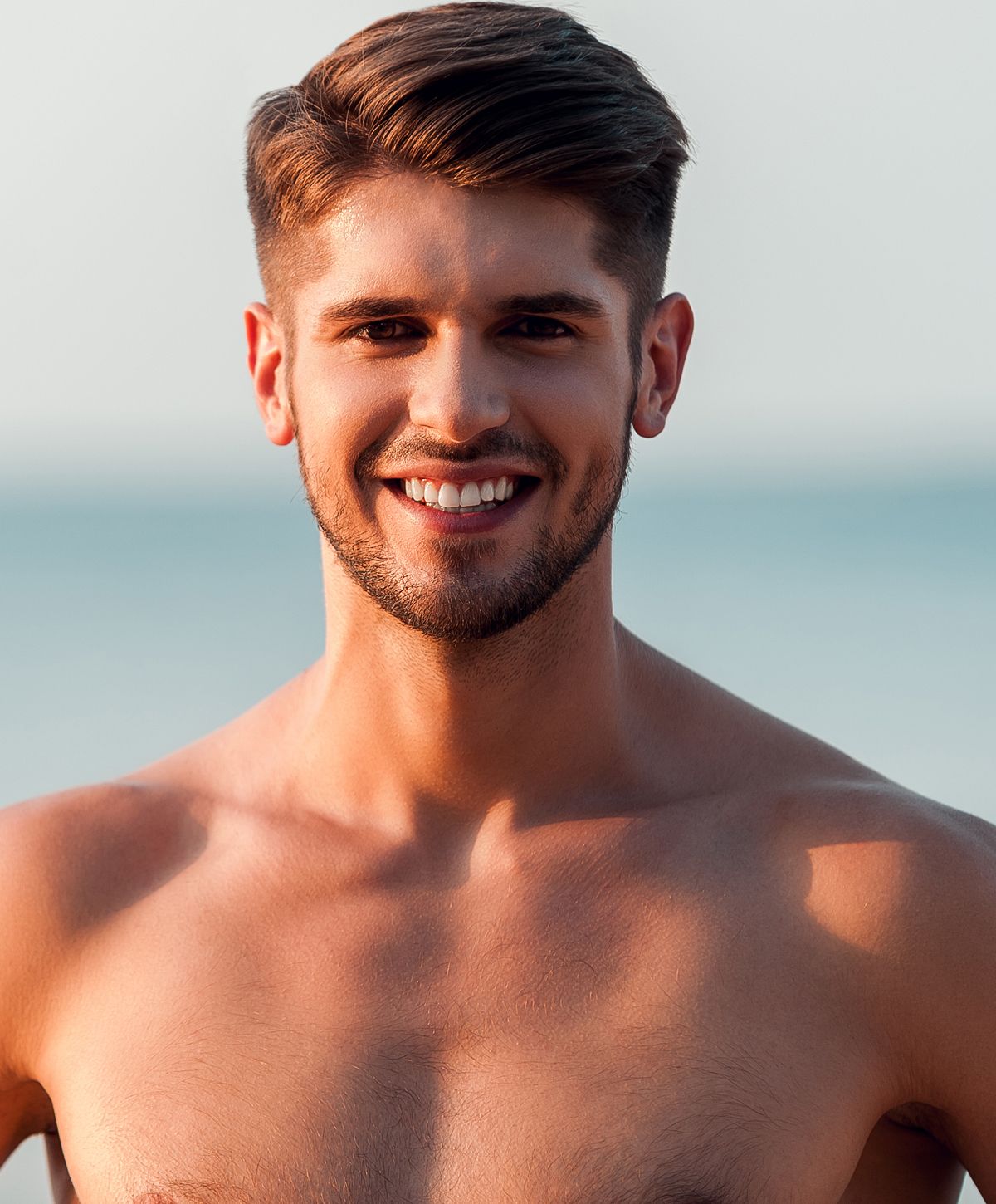 Smiling man with short hair by the beach.