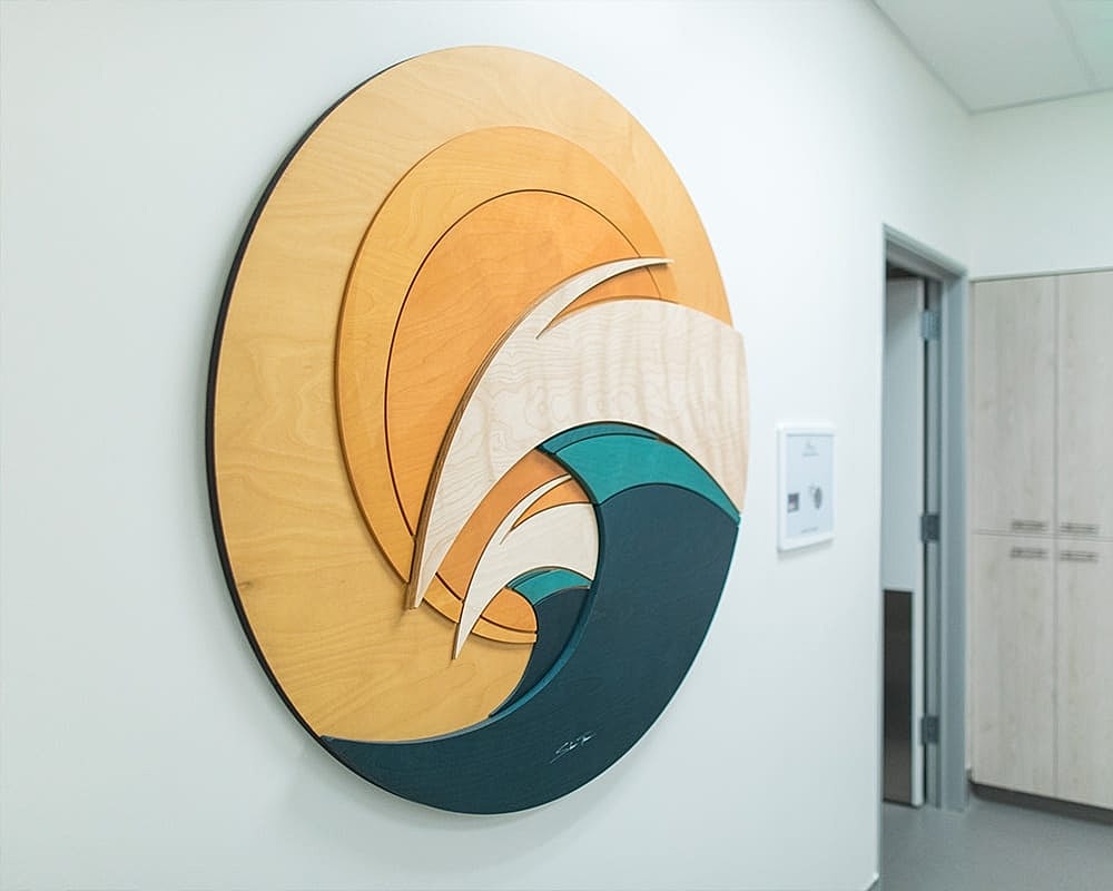 Wooden wall art depicting waves and sunset.