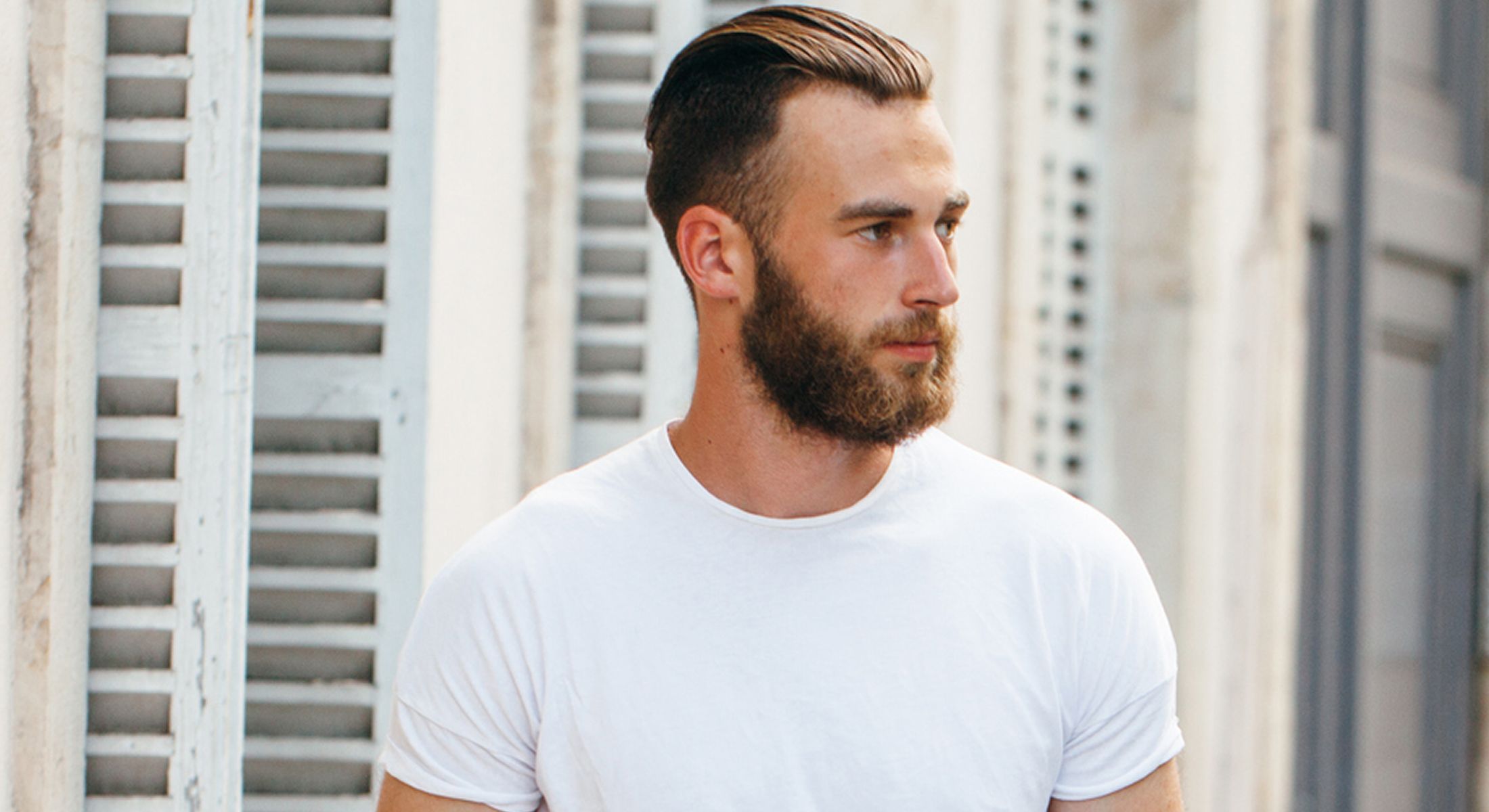 Man with beard wearing a white t-shirt.
