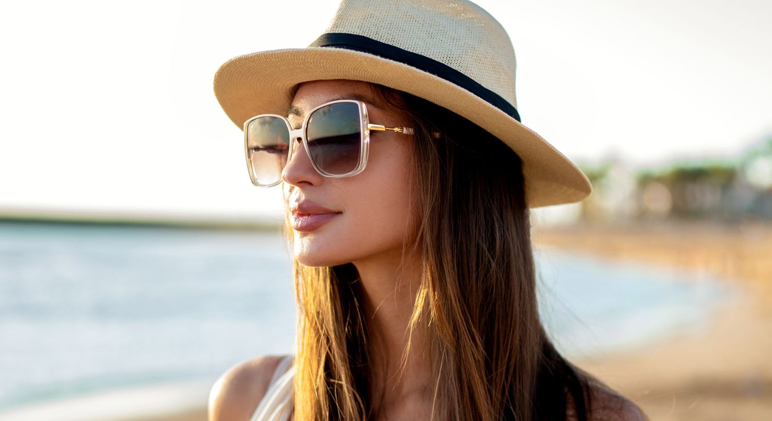 Woman in sunglasses and hat at the beach.